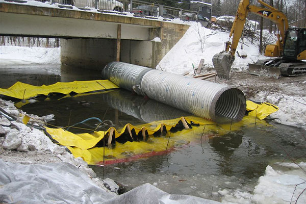 Installation de deux batardeaux Water-Gate© tête bêche avec tube de dérivation placé sur les barrages flexibles.
