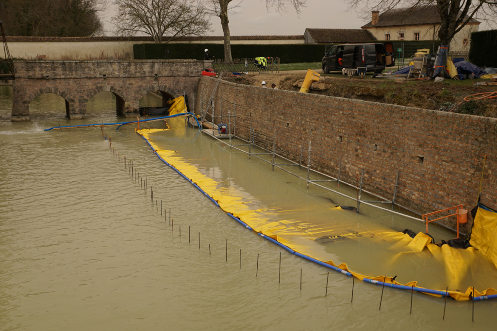 Pompage des douves avec batardeau souple, niveau d’eau en baisse côté zone de travaux