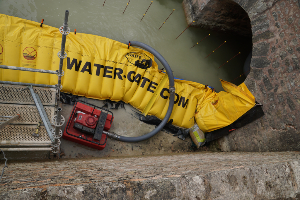 Pompe flottante d’appoint et charnière de batardeau souple posée sur le sol dans les douves du château
